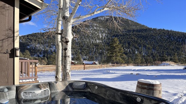 Uma banheira de hidromassagem com vista para uma paisagem nevada e uma montanha ao fundo.