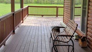 Eine überdachte Holzterrasse mit einer Bank und Blick auf eine Rasenfläche.