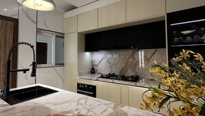 A modern kitchen with a marble countertop, black appliances, and pendant lighting. - Vika Luxury 3 Bedroom Serviced Apartment (Abuja)