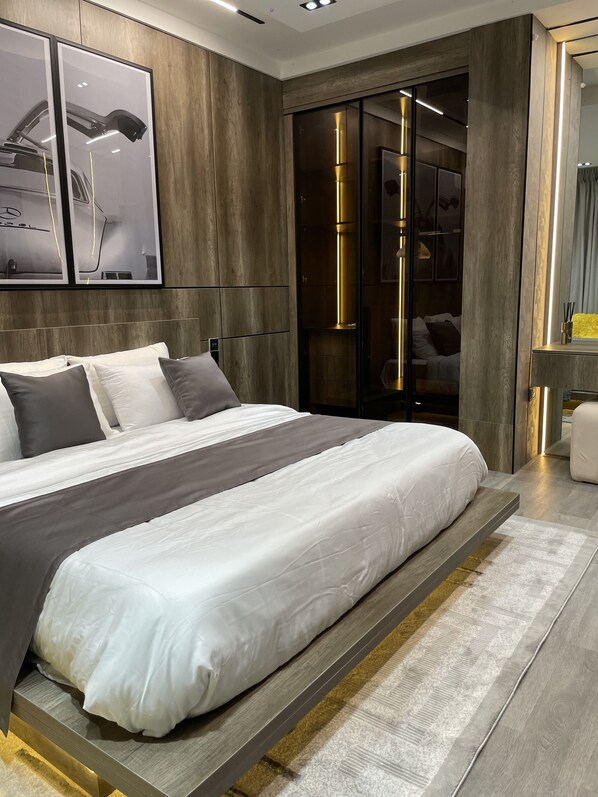 A modern bedroom with a large bed, a wardrobe, and a mirror.