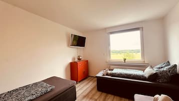 A bedroom with two beds, a TV, a window with a view, and a red cabinet.