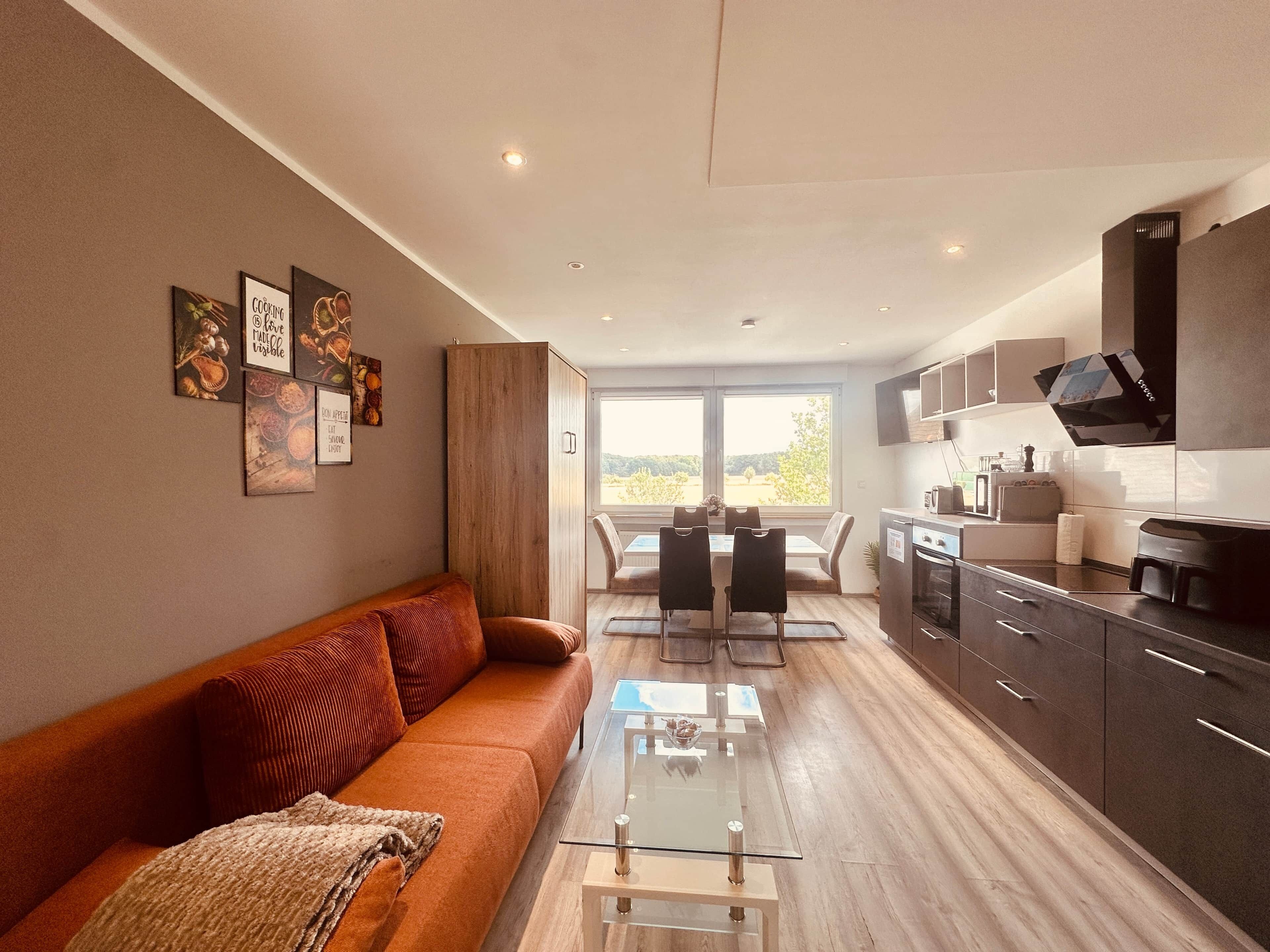 Un salon moderne avec un canapé, une table basse en verre et un coin repas comprenant des chaises et une table.