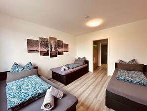 A hotel room with two beds, a sofa bed, a wall with artwork, and a hallway leading to another room. - 90 I Sauna I 7 Beds I To the beautiful view (Dortmund)