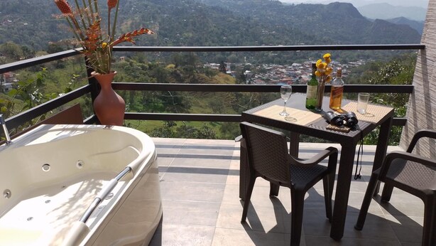 Un balcone con una vasca idromassaggio, un tavolo con sedie e un vaso di fiori.