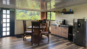 Una cucina con zona pranzo, ampie finestre e vista sul verde.