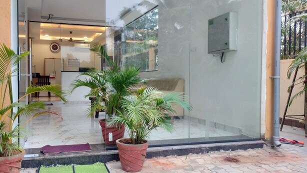 A modern entrance with potted plants, a reception desk, and a glass door leading inside. - Hotel PSR Executive Rooms by VINHOTELS (Bengaluru)