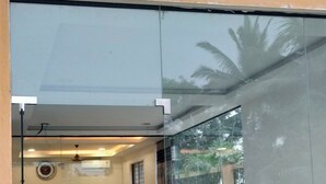 A reception area with a glass wall, potted plants, and a reception desk. - Hotel PSR Executive Rooms by VINHOTELS (Bengaluru)