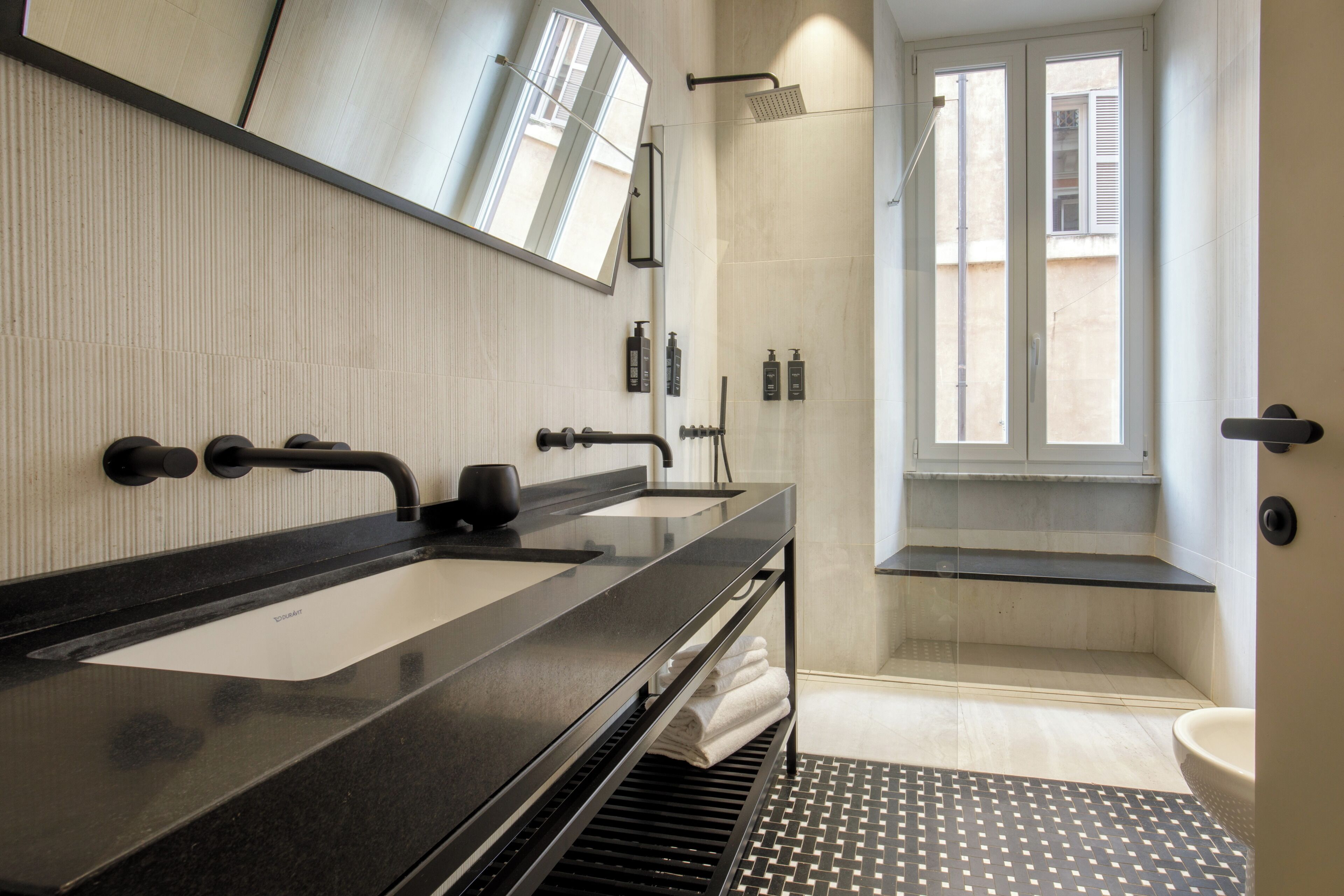 Une salle de bain moderne avec un lavabo, un miroir et une douche noirs.