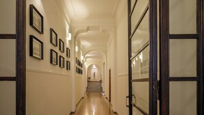 A hallway with framed pictures on the walls, a staircase, and a door with frosted glass panels. - Ripetta Luxury Apartments (Rome)