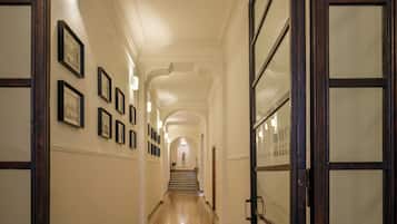 Un couloir orné de tableaux encadrés, un escalier et une porte dont les panneaux sont en verre dépoli.