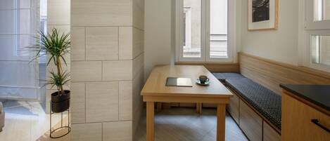 A modern kitchen with a wooden table, a bench, and a potted plant.