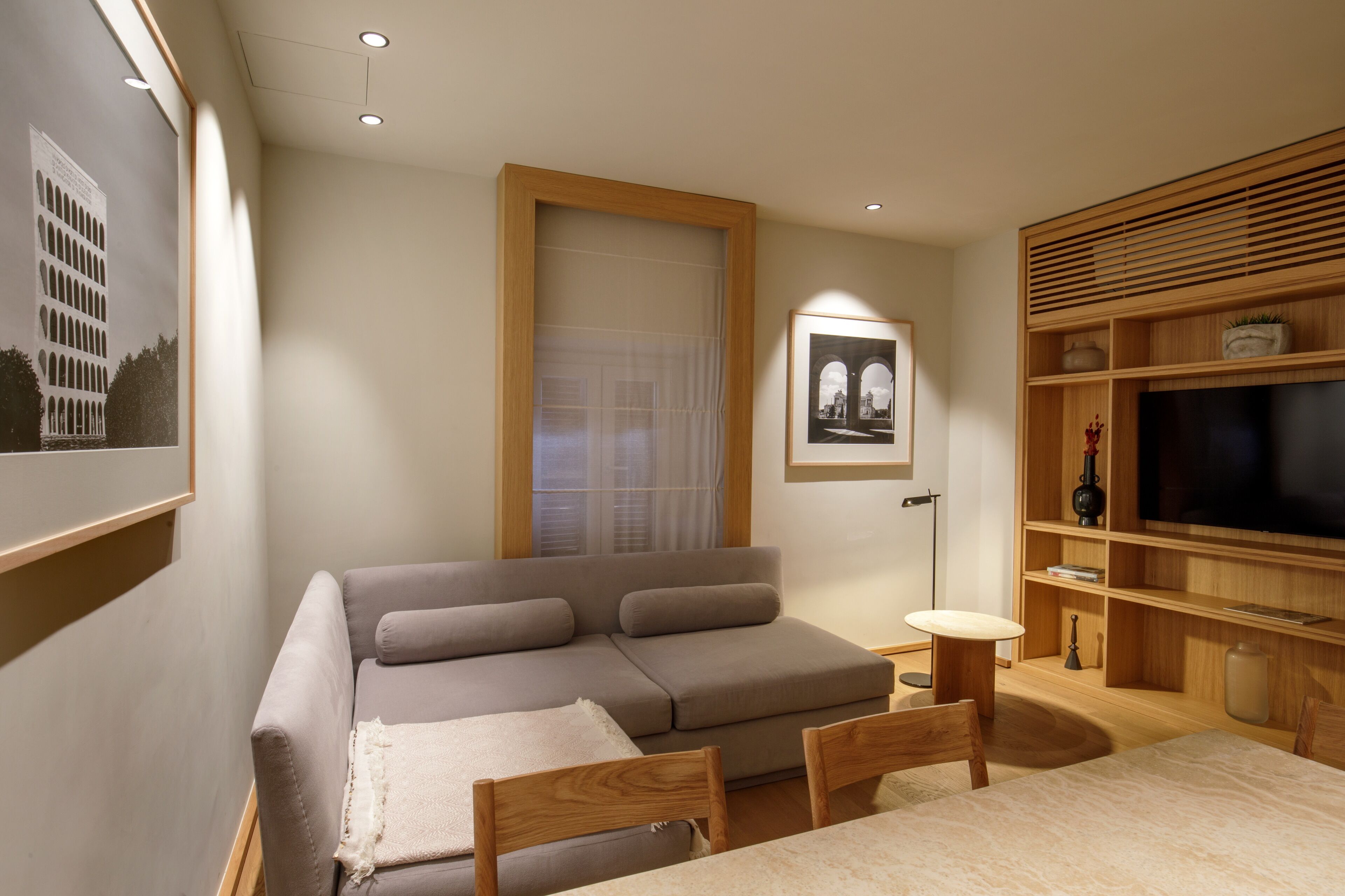 A modern living room with a sofa, a small table, and a TV shelf.