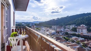 A balcony with a table and chairs, overlooking a cityscape with buildings and a hill. - Apartamento aconchegante. Vista incrível (Águas de Lindóia)