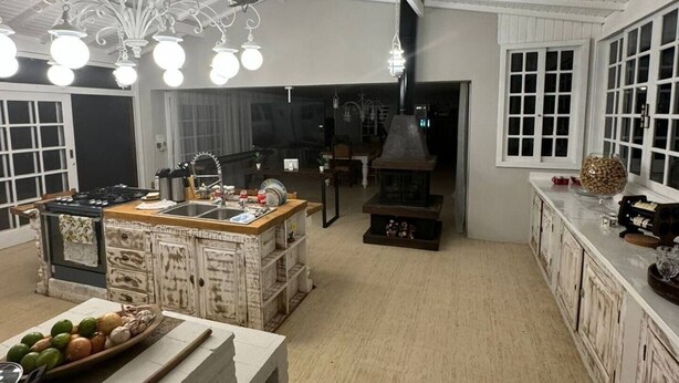 A spacious kitchen with white cabinetry, a central island, and a large stove. - Casa Iracema da Serra (Vale do Paquequer)