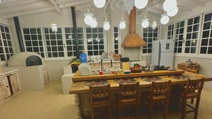 A spacious kitchen with a large island, white cabinetry, and a modern chandelier. - Casa Iracema da Serra (Vale do Paquequer)