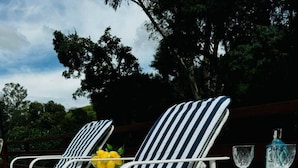 Two striped lounge chairs with a table and a glass of liquor between them. - Casa Iracema da Serra (Vale do Paquequer)