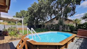 A wooden swimming pool with a deck, surrounded by a gravel area and a wooden deck. - Maison Familiale Entre mer et Centre-ville (Ondres)