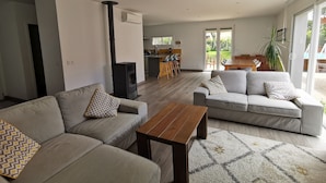 A modern living room with two sofas, a coffee table, and a kitchen in the background. - Maison Familiale Entre mer et Centre-ville (Ondres)