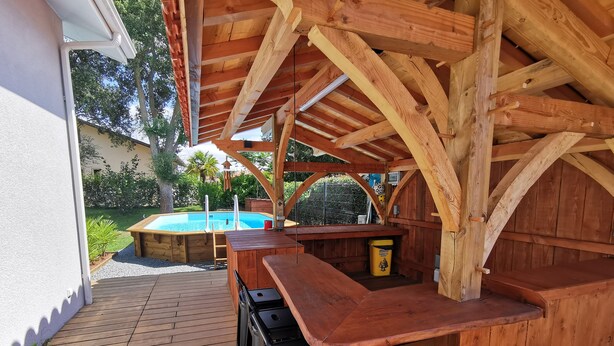 A wooden deck with a pool and a bar area. - Maison Familiale Entre mer et Centre-ville (Ondres)