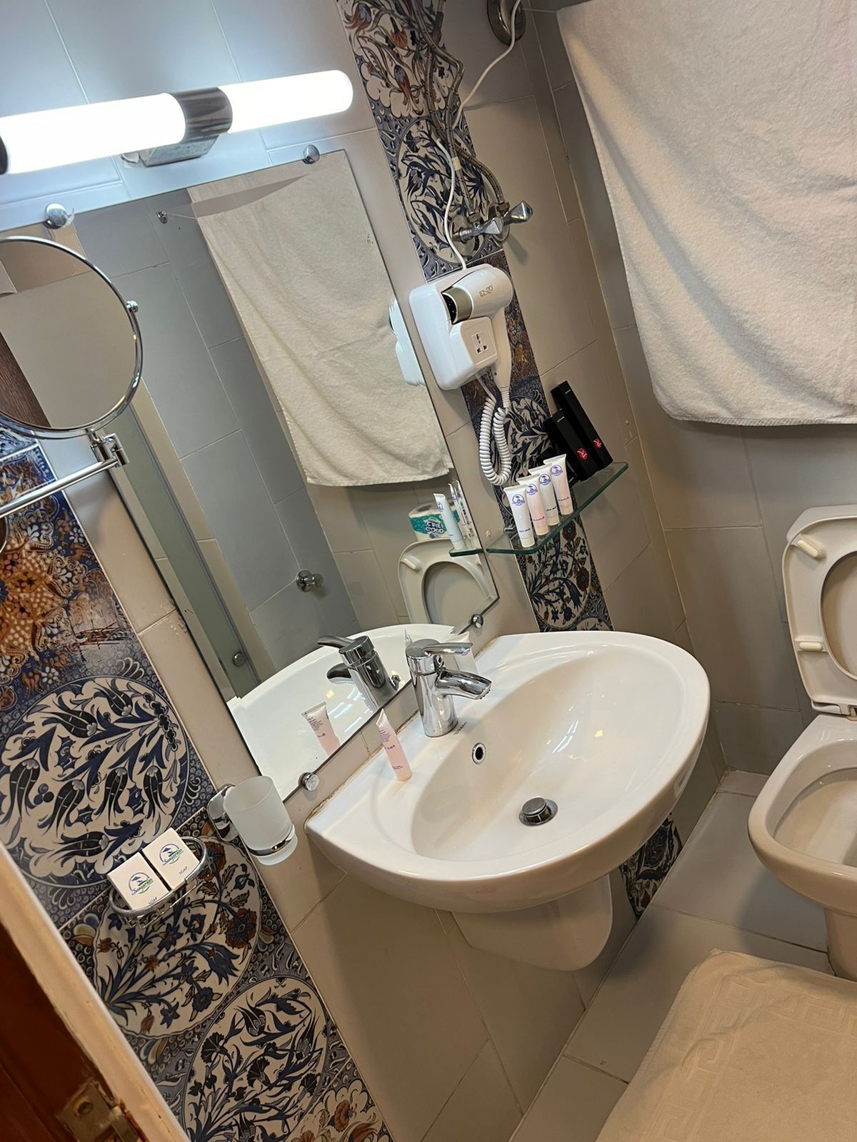Une salle de bain avec un grand lavabo, un miroir, des toilettes et une serviette accrochée au mur.