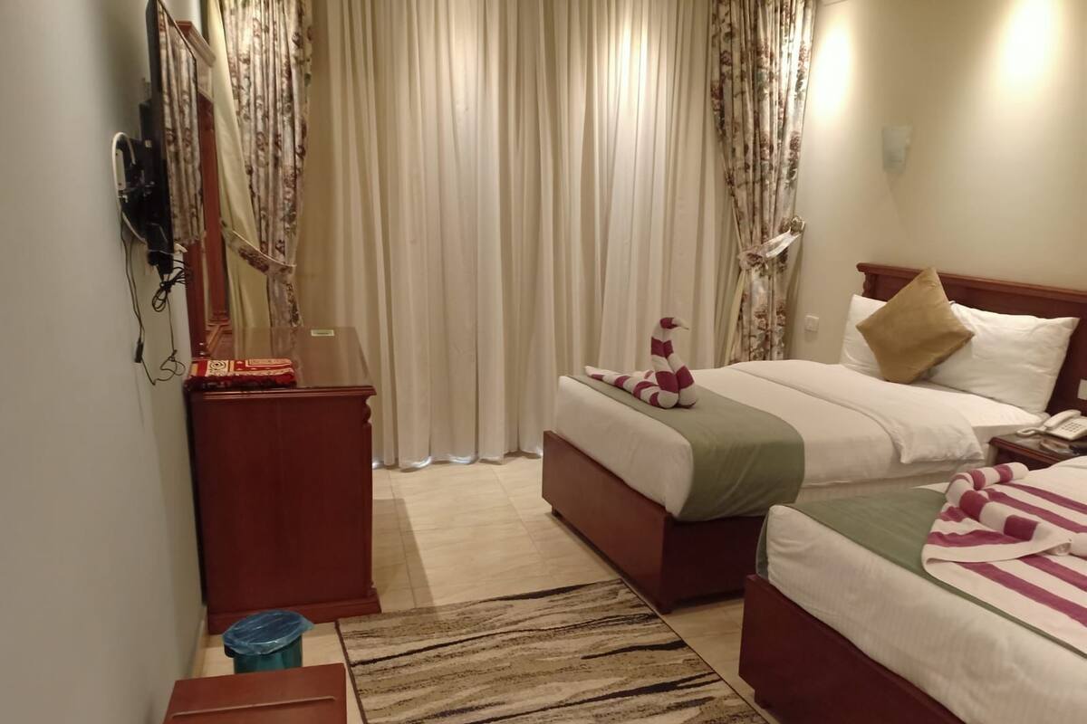 Ein Hotelzimmer mit zwei Betten, einem Holzschrank, einem Schreibtisch und einem Telefon.
