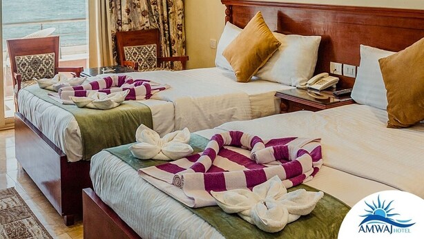 A hotel room with two beds, a view of the sea, and a sign indicating "Maximum Luxury". - Amwaj Hotel (Alexandria)