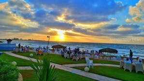 A coastal resort with a sunset view, outdoor seating areas, and a pool. - Amwaj Hotel (Alexandria)