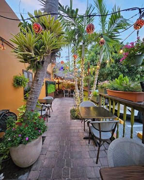 An outdoor patio area with stone flooring, potted plants, and outdoor seating.