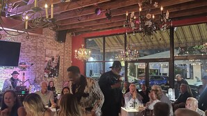 En restaurang med synliga träbjälkar, kristallkronor och gäster som äter.