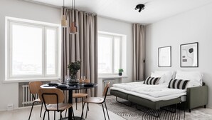 A modern bedroom with a bed, bedside tables, and a dining area with chairs and a table. - Prime Apartments Pori Central (Pori)