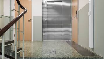 Un ascensor modern amb acabat metàl·lic, una porta de fusta i un sòl amb moqueta verda que porta el número 4.