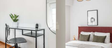 Una habitación con escritorio, silla y cama con cabecera roja.