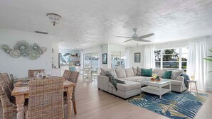 A spacious living room with a dining area, a sofa set, and a ceiling fan.