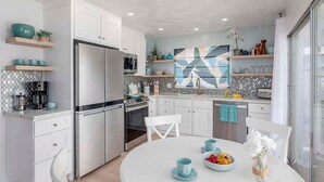 A modern kitchen with white cabinetry, stainless steel appliances, and a central island.