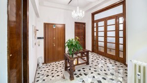 A hallway with a tiled floor, wooden doors, and a chandelier. - Apartment via Milizia 3br/3bt (Roma)