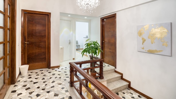 A hallway with a wooden door, a potted plant, a world map on the wall, and a chandelier. - Apartment via Milizia 3br/3bt (Roma)