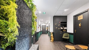 A hallway with a green wall, a black door, and a small table with chairs. - L'App-Art (Nice)