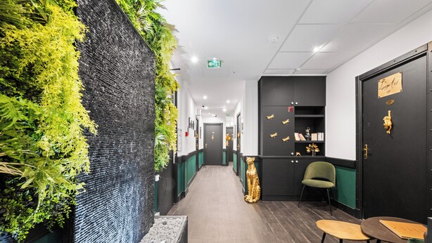 A hallway with a green wall, a black door, and a small table with chairs. - L'App-Art (Nice)