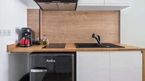 A compact kitchenette with a Bosch coffee maker, a sink, and an Amica dishwasher. - L'App-Art (Nice)