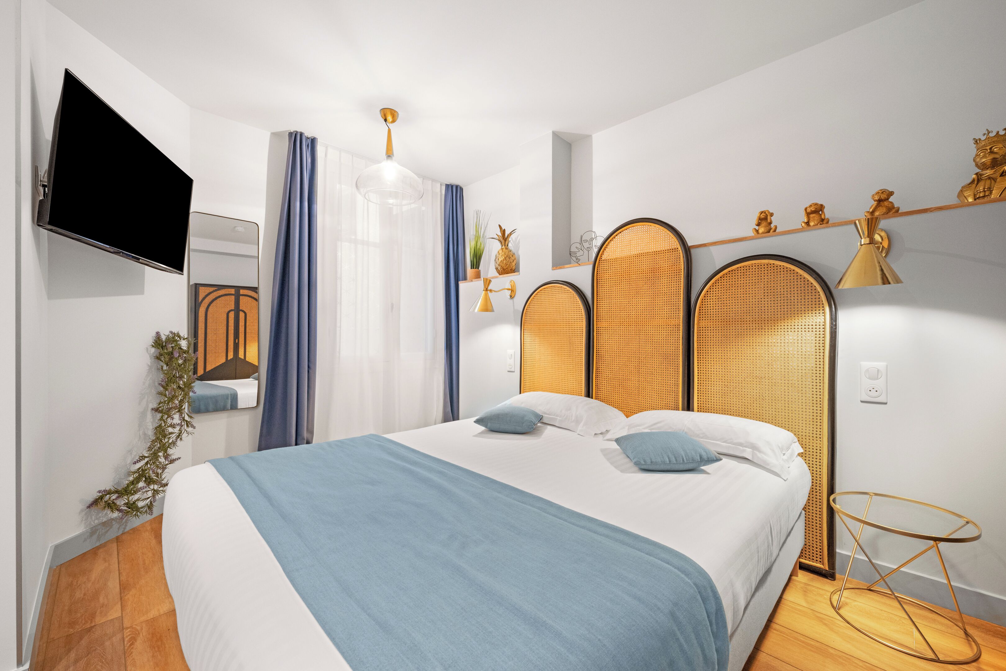 Ein modernes Schlafzimmer mit einem Bett, einem an der Wand befestigten Fernseher und einem kleinen Tisch mit einer Lampe.