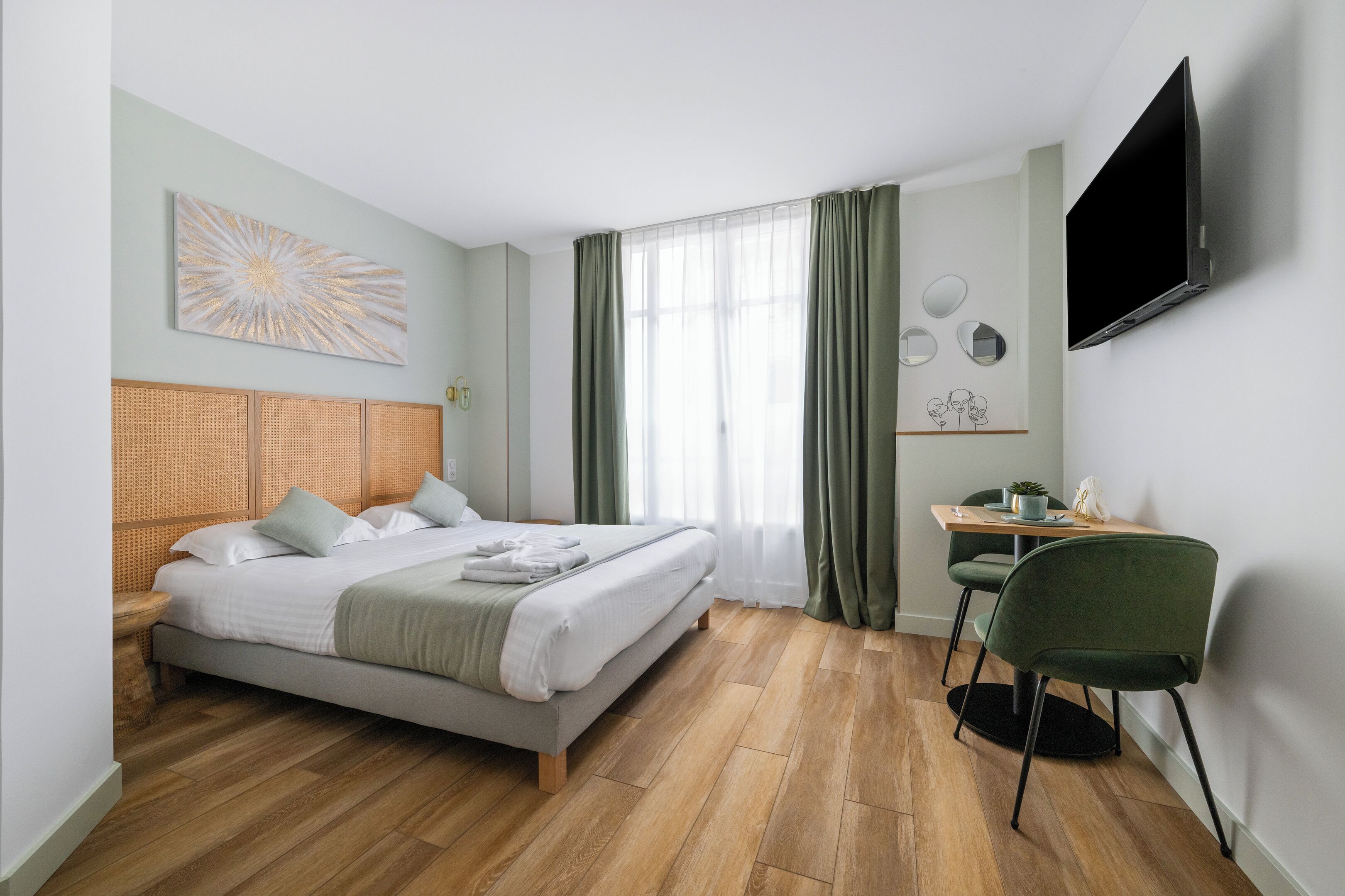 Ein modernes Hotelzimmer mit Bett, Schreibtisch, Sessel, Fernseher und einem fenster mit Vorhängen.