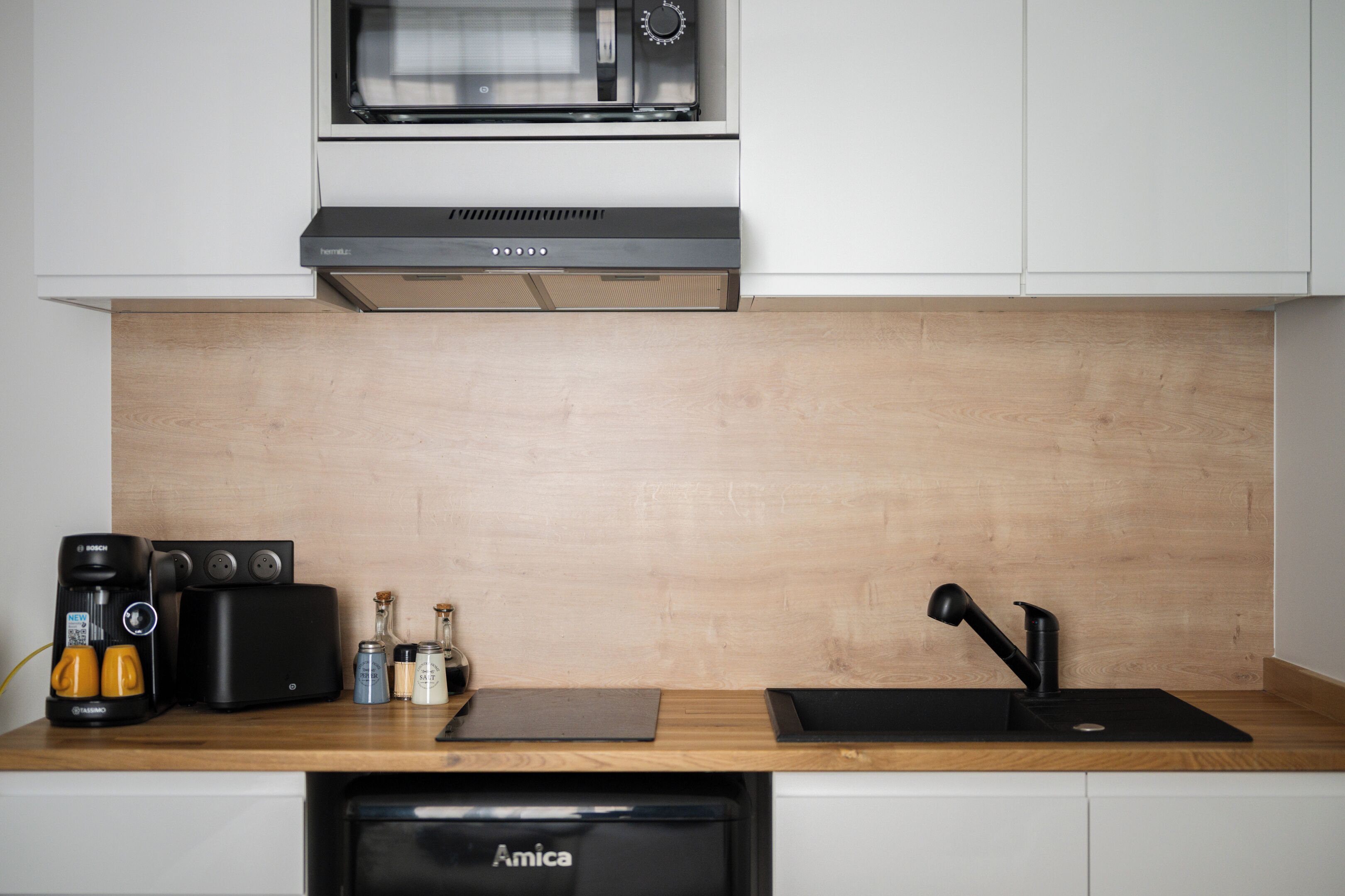 Una cocina moderna equipada con microondas, tostadora, cafetera y lavabo.