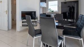 A modern kitchen with a dining area, featuring a TV, black chairs, and a large window. - Two-bedroom apartmetn with sea view (Novalja)