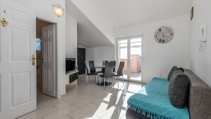 A spacious living area with a sofa, a dining table with chairs, and a TV. - Two-bedroom apartmetn with sea view (Novalja)