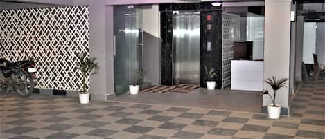 A checkered floor, a motorcycle, potted plants, and an elevator.