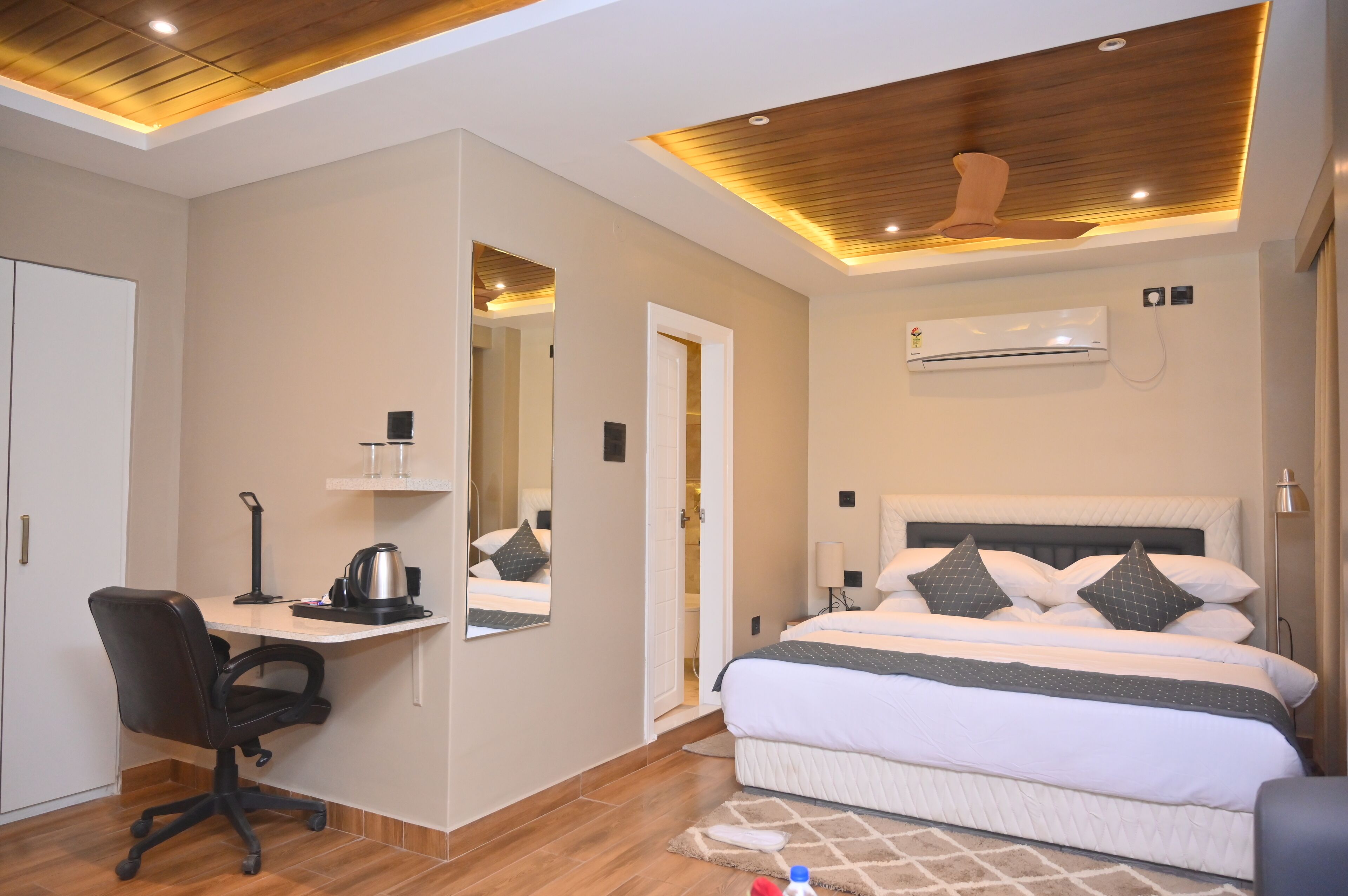 A hotel room with a bed, desk, chair, and ceiling fan.