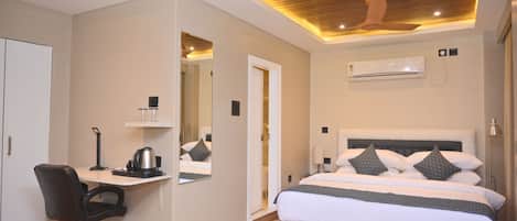 A hotel room with a bed, desk, chair, and ceiling fan.