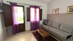 A living room with a sofa, a coffee table, and curtains on the windows. - Casa Mim in Cabras (Cabras)