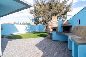 A backyard with a brick oven and a blue wall.