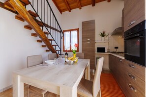 Une cuisine moderne avec un escalier en bois, une table à manger avec des chaises et un four encastré.